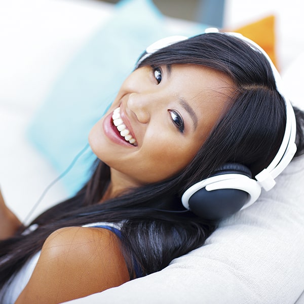 A young woman with porcelain veneers smiling while listening to music