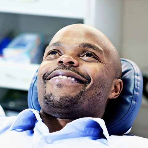 Man with beard smiling while resting on dentist chair