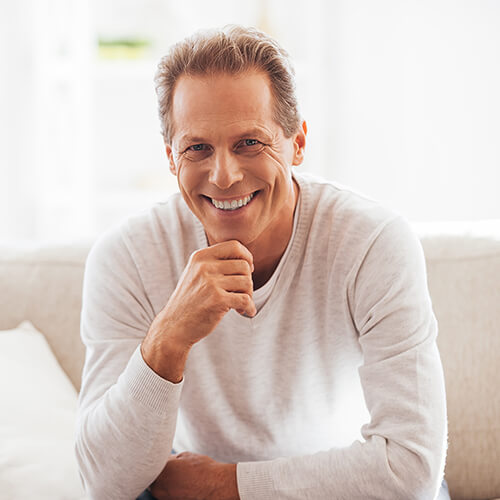 Mature man with white t-shirt smiling on couch