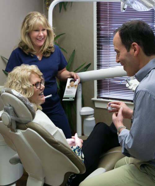 Dr. Rosenberg speaking to a patient with the help of his dental assistant