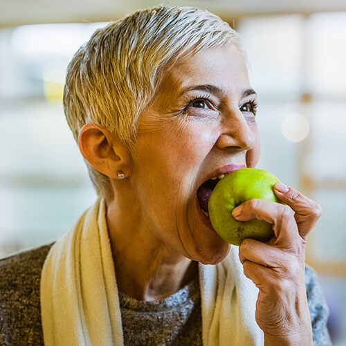 A mature woman bitting on an apple