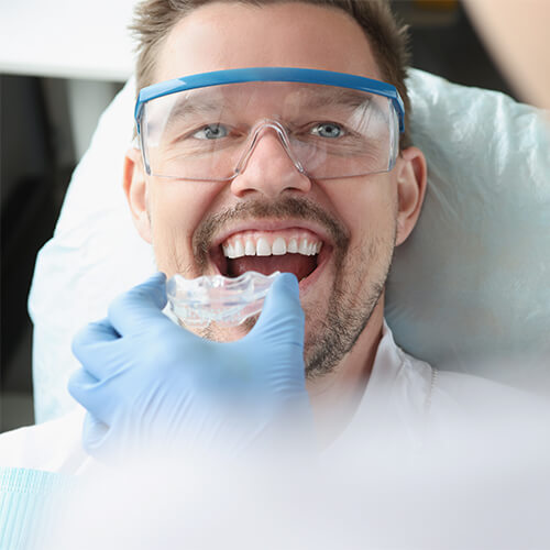 A man wearing protection glasses at the dentist while getting his new mouthguards
